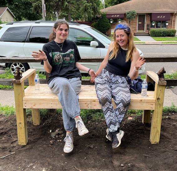 sarah and alayna sitting on a bench in the victoria community garden